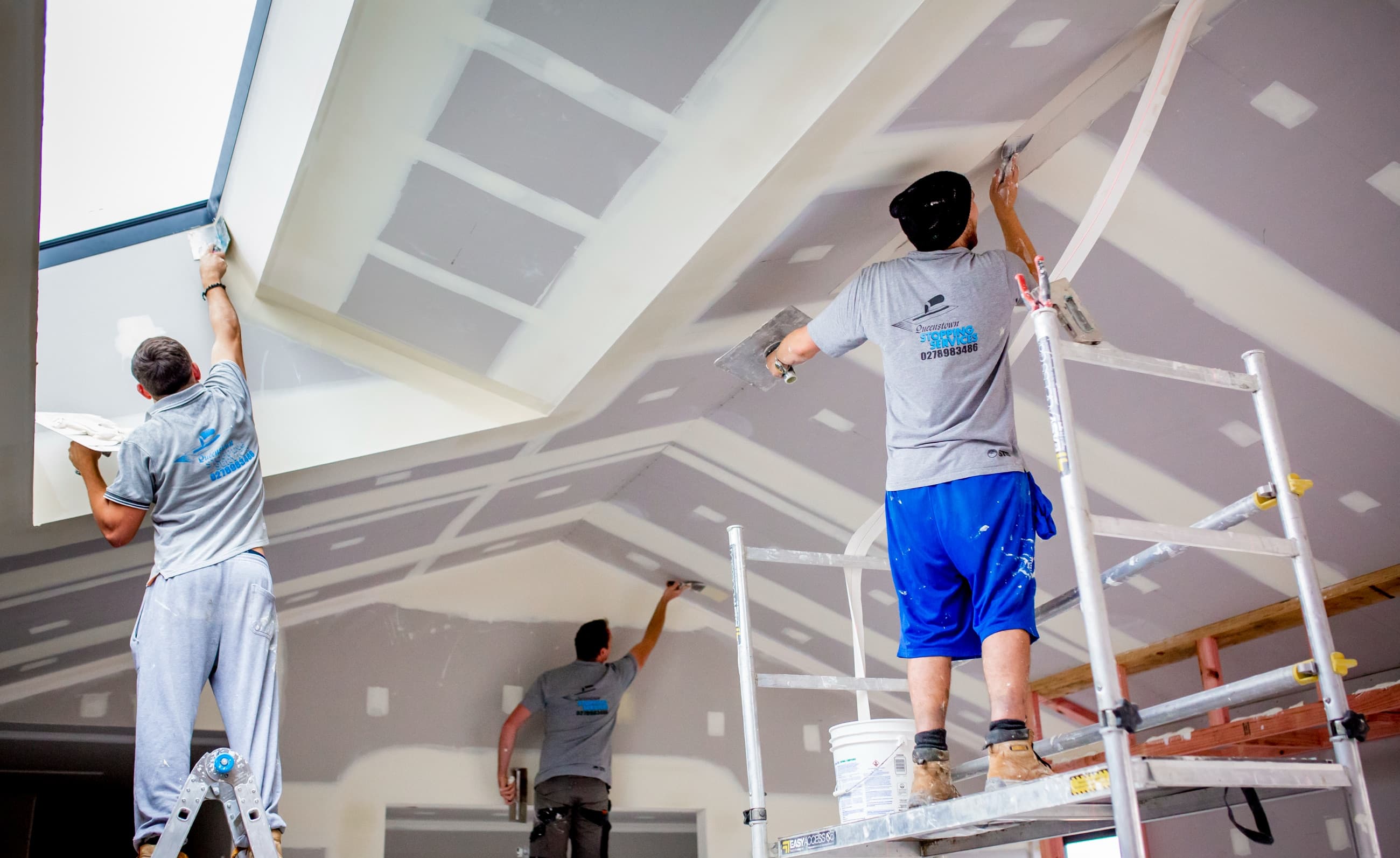 Queenstown Stopping Services team stopping plasterboard in a high-end interior with complex ceiling geometry and skylights