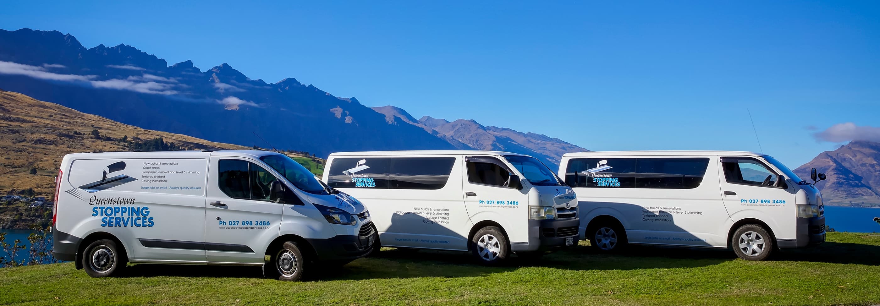 Three Queenstown Stopping Services vans with the Remarkables mountain range behind